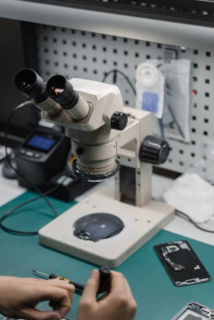 High angle shot of a microscope in an electronics repair setup with tools and components.