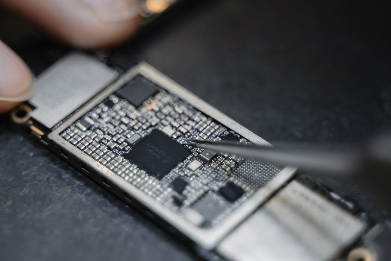 about-02 Detailed view of a technician using tweezers to fix an electronic circuit board.