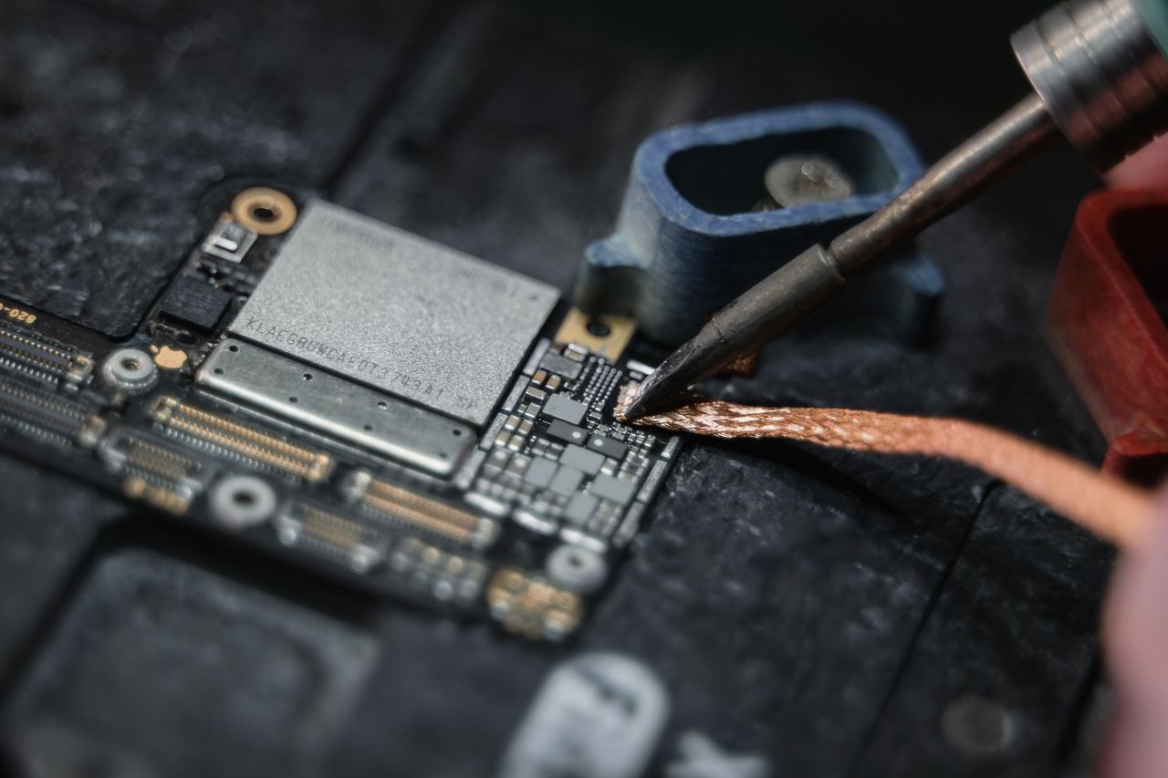 Detailed close-up of a soldering iron working on a circuit board, showcasing electronics repair.
